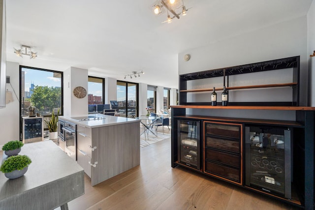 kitchen featuring wine cooler, floor to ceiling windows, a center island, black electric stovetop, and light hardwood / wood-style floors