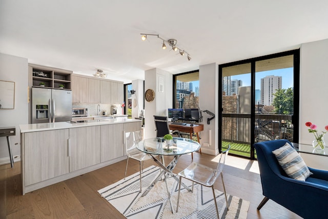 kitchen with decorative backsplash, expansive windows, stainless steel appliances, light brown cabinets, and light hardwood / wood-style flooring