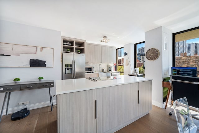 kitchen with black electric stovetop, stainless steel fridge, light brown cabinetry, and a kitchen island