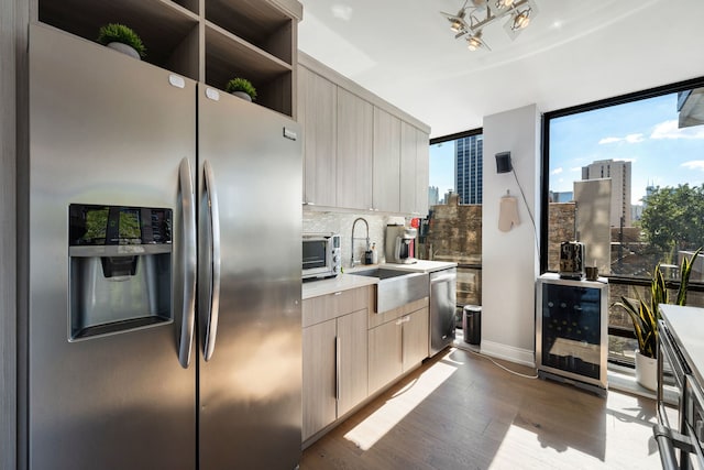 kitchen featuring appliances with stainless steel finishes, sink, beverage cooler, dark hardwood / wood-style flooring, and light brown cabinets