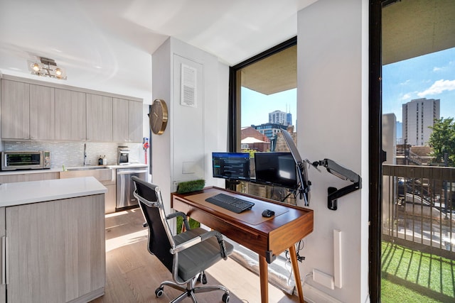 office area with sink, light hardwood / wood-style flooring, and a wall of windows