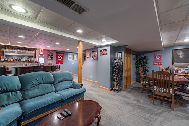 living room featuring indoor bar, light carpet, and a drop ceiling