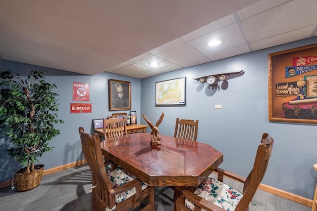 carpeted dining area featuring a paneled ceiling