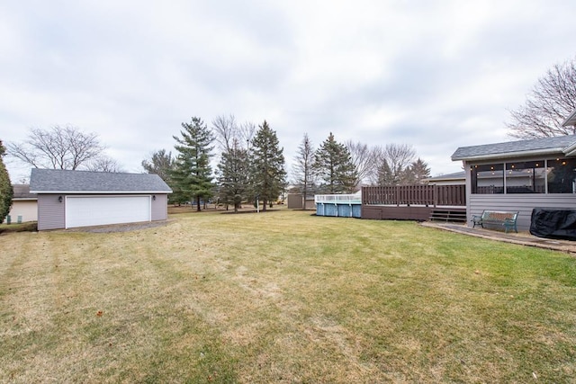 view of yard featuring a pool side deck, a garage, an outdoor structure, and a sunroom