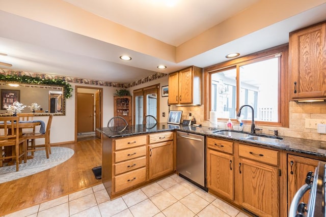 kitchen featuring sink, dishwasher, tasteful backsplash, kitchen peninsula, and dark stone counters