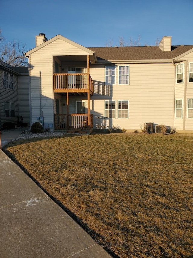 rear view of property featuring a balcony, a yard, and central air condition unit