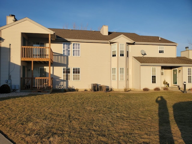 rear view of property with a yard, a balcony, and central air condition unit