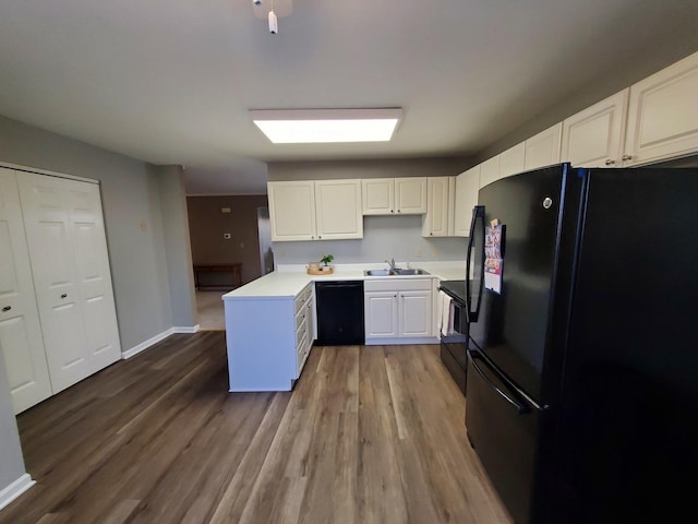 kitchen featuring wood-type flooring, sink, white cabinets, and black appliances