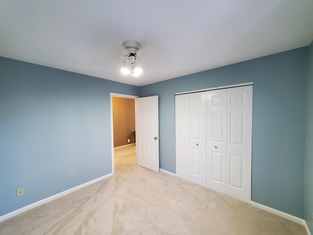 unfurnished bedroom featuring ceiling fan, light colored carpet, and a closet