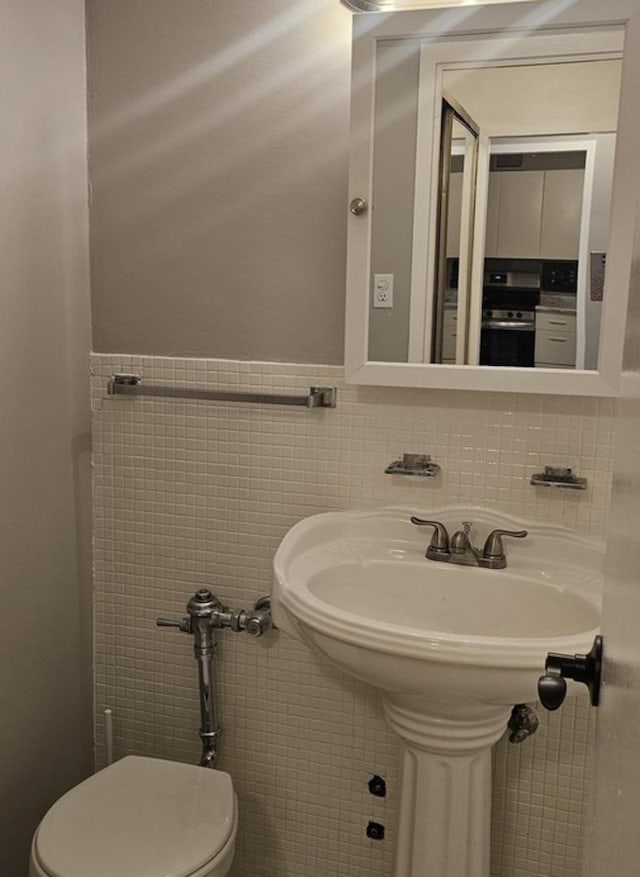 bathroom featuring toilet and tile walls