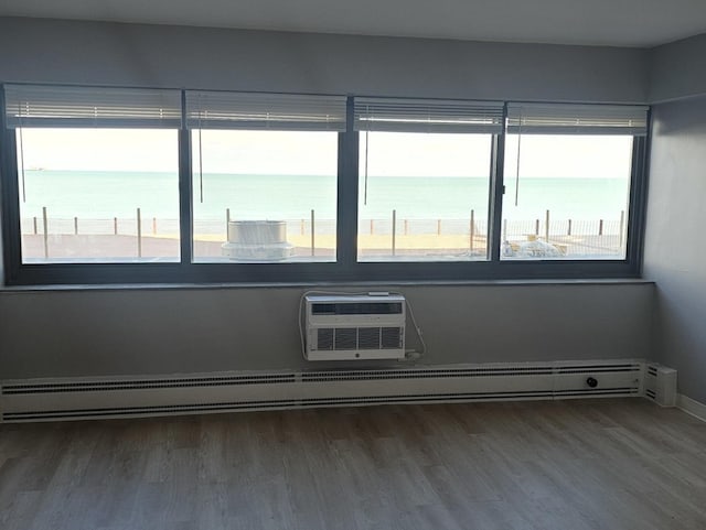 spare room with hardwood / wood-style flooring, a water view, and a wall unit AC