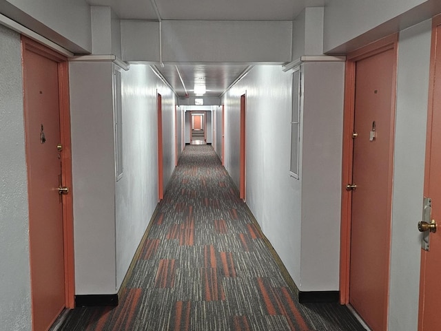 hall with dark colored carpet