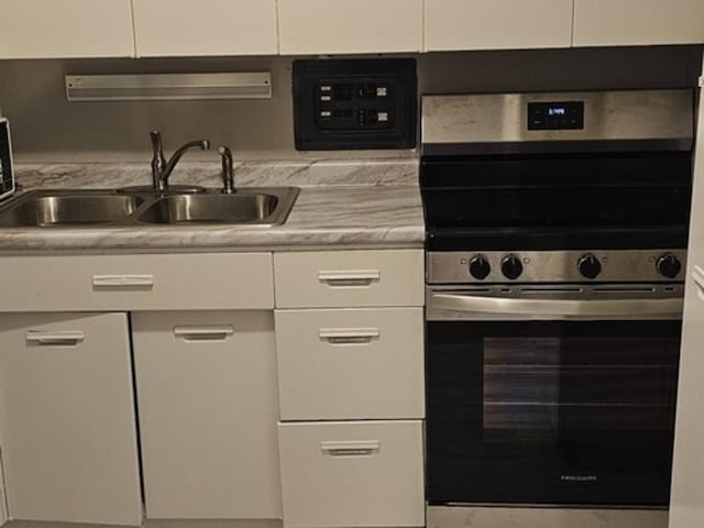 kitchen with white cabinetry, stainless steel electric stove, and sink