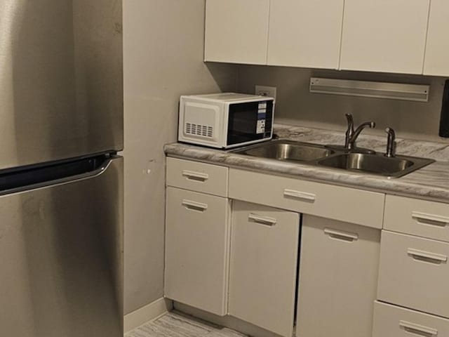 kitchen with sink, stainless steel fridge, and white cabinets