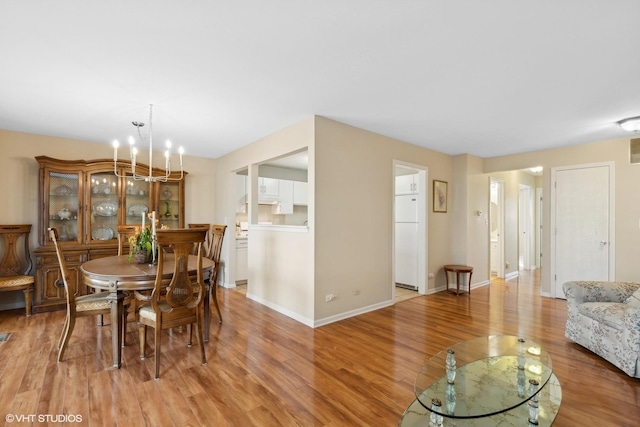 dining space with light hardwood / wood-style flooring and a notable chandelier