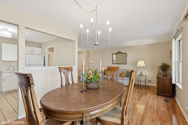 dining space featuring light hardwood / wood-style floors and a notable chandelier