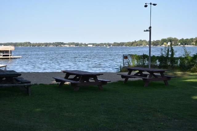 view of dock with a water view and a yard