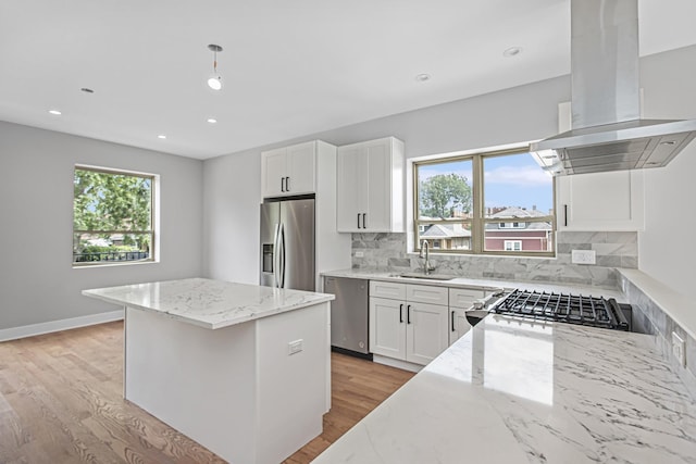 kitchen featuring pendant lighting, light stone counters, island range hood, and stainless steel appliances