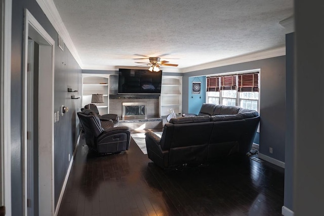 living room with crown molding, a textured ceiling, dark hardwood / wood-style flooring, ceiling fan, and a tiled fireplace