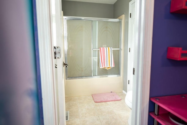 bathroom featuring bath / shower combo with glass door, tile patterned floors, and toilet