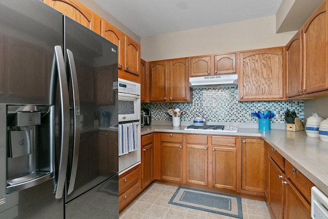 kitchen featuring dishwashing machine, double oven, fridge with ice dispenser, stainless steel gas cooktop, and decorative backsplash