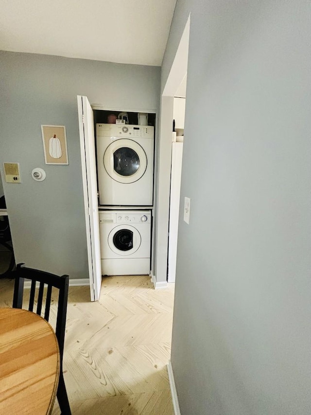 clothes washing area featuring stacked washer / drying machine and light parquet flooring