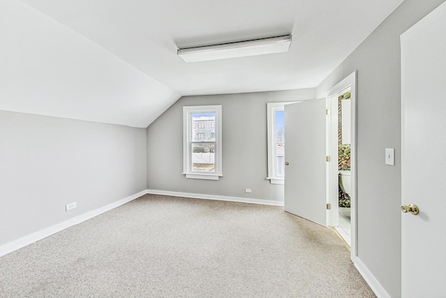 additional living space with lofted ceiling, a healthy amount of sunlight, and light colored carpet