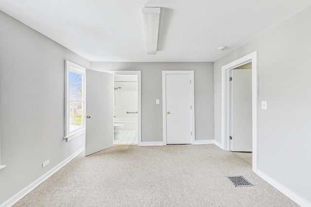 unfurnished bedroom with ensuite bathroom and light carpet