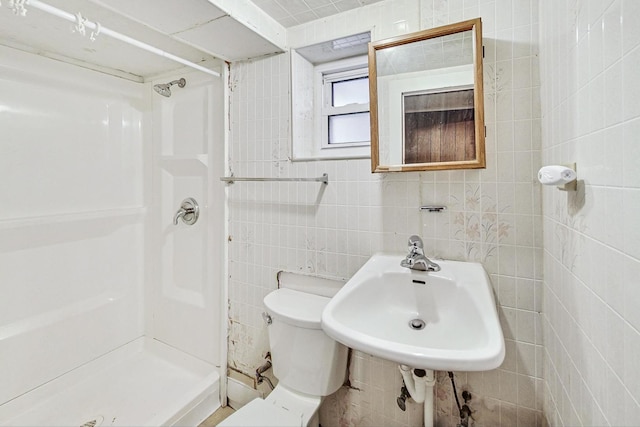 bathroom with toilet, sink, tile walls, and a shower