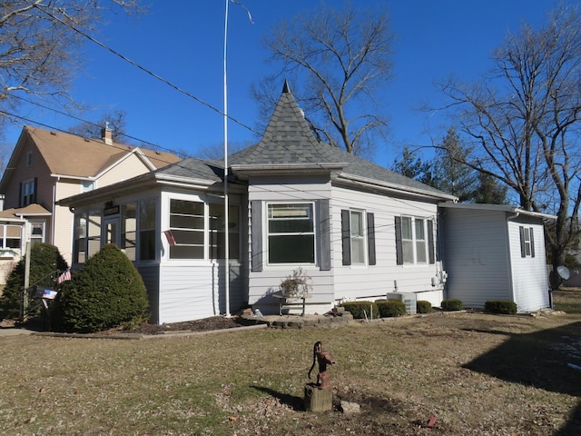 exterior space featuring a sunroom, cooling unit, and a front lawn