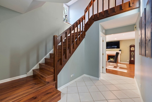 stairway with tile patterned flooring and a fireplace