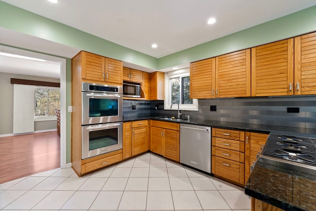 kitchen featuring stainless steel appliances, sink, light tile patterned floors, and backsplash