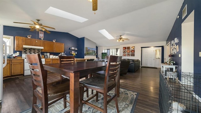 dining space featuring ceiling fan, dark wood-type flooring, and vaulted ceiling with skylight