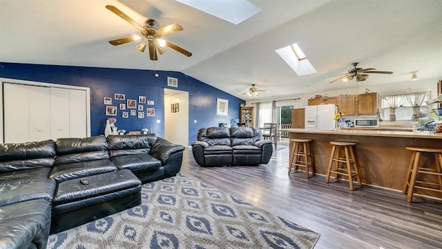 living room with hardwood / wood-style flooring, lofted ceiling with skylight, a wealth of natural light, and ceiling fan