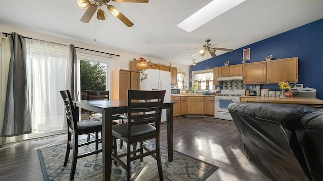 kitchen with a healthy amount of sunlight, vaulted ceiling with skylight, backsplash, and white appliances