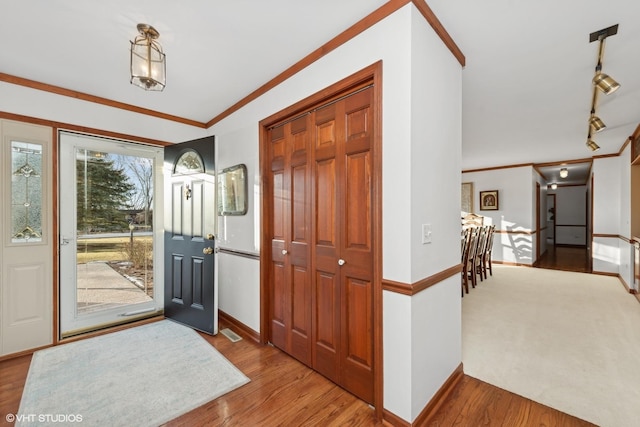 foyer featuring hardwood / wood-style flooring, track lighting, and ornamental molding