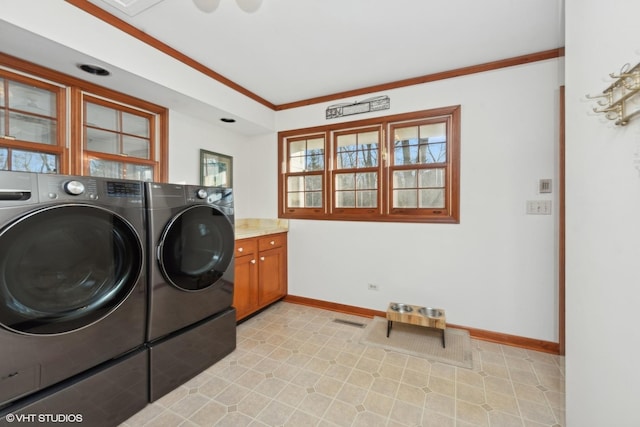 washroom with cabinets, ornamental molding, and washing machine and clothes dryer