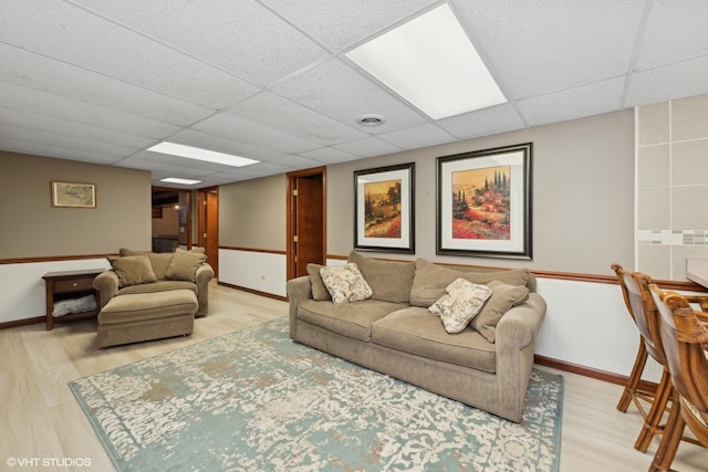 living room featuring light hardwood / wood-style floors and a drop ceiling