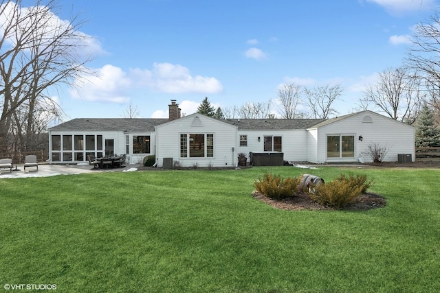 rear view of house featuring a hot tub, a sunroom, a yard, and a patio area