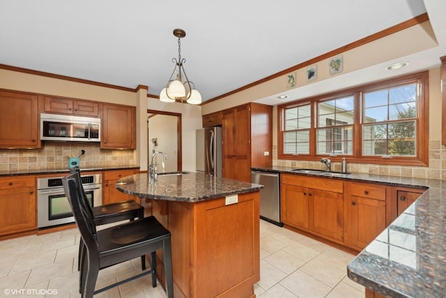 kitchen with appliances with stainless steel finishes, sink, pendant lighting, and a kitchen island with sink