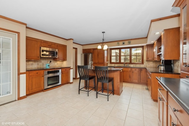 kitchen featuring tasteful backsplash, a kitchen bar, hanging light fixtures, a center island, and stainless steel appliances