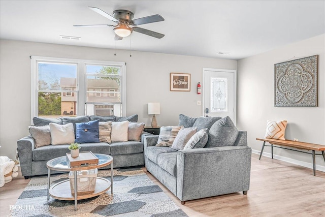 living room with a ceiling fan, baseboards, visible vents, and light wood-style floors