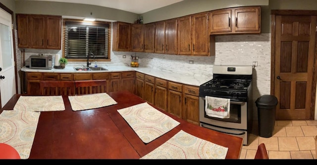 kitchen with stainless steel appliances, tasteful backsplash, sink, and light tile patterned floors