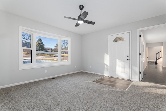 entryway with ceiling fan and dark carpet