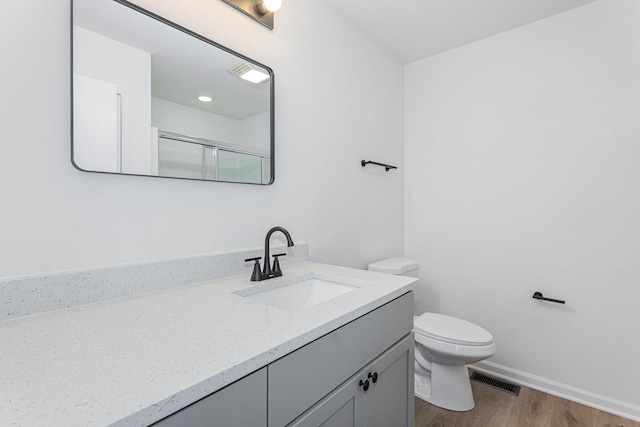 bathroom featuring vanity, a shower with shower door, wood-type flooring, and toilet