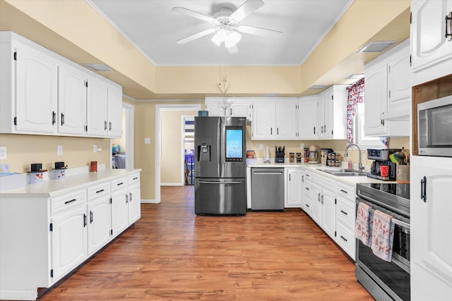 kitchen with sink, white cabinetry, crown molding, stainless steel appliances, and light hardwood / wood-style floors