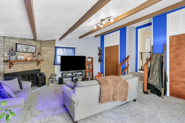 carpeted living room with beamed ceiling and a stone fireplace