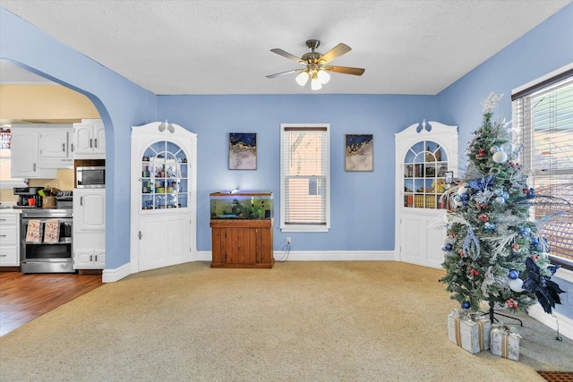 living room with ceiling fan, light colored carpet, a textured ceiling, and a wealth of natural light