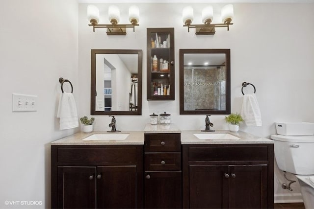 bathroom featuring a shower with door, vanity, and toilet