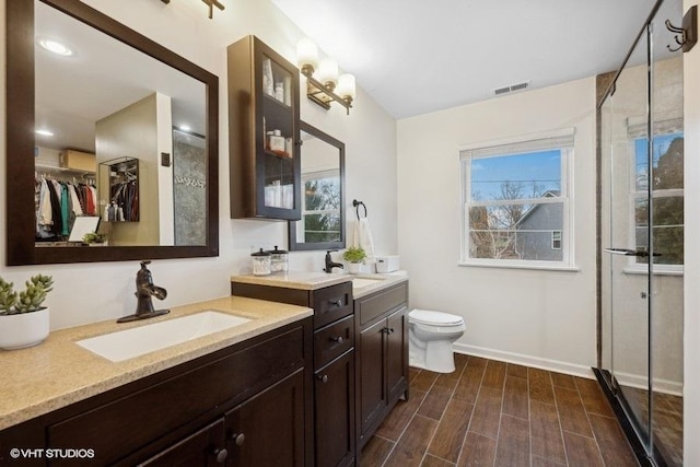 bathroom featuring hardwood / wood-style flooring, vanity, toilet, and an enclosed shower